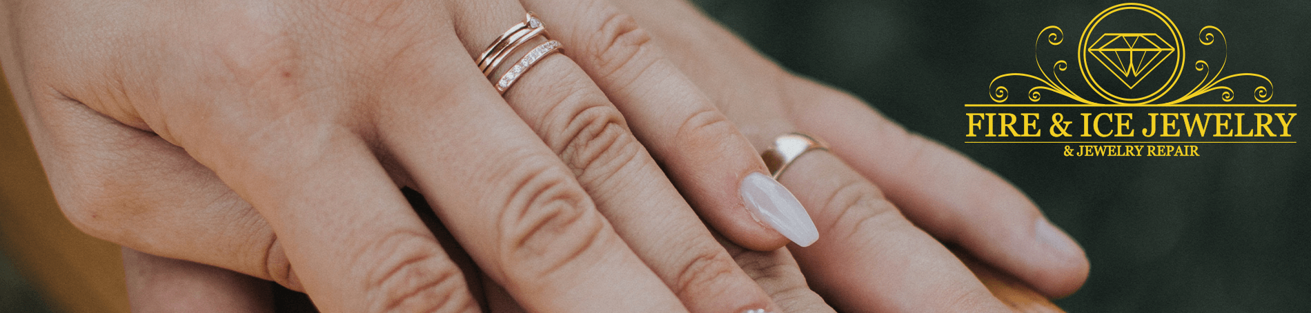 Image of a lady's hand over a man's hand, both wearing a stylish gold wedding ring, resting on a wooden beam
