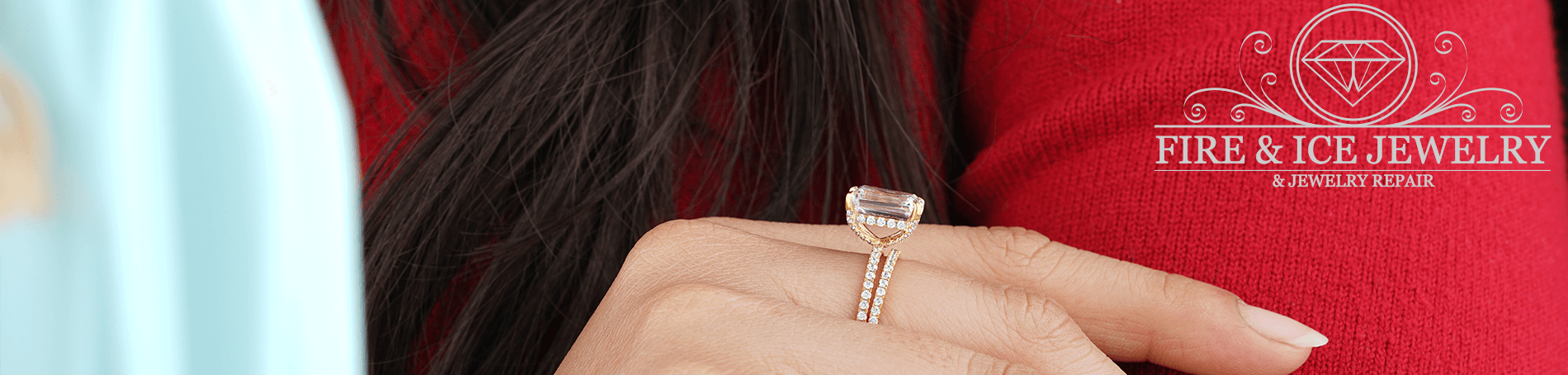 Image of a lady's hand wearing a large single diamond ring. Her ehand is crossed over her other arm, she is wearing a luxurious red wool sweater
